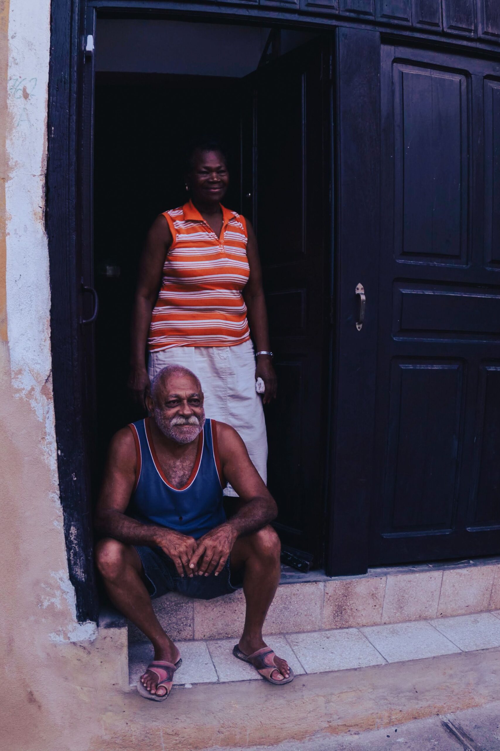Pareja mayor sonriendo en la entrada de su casa