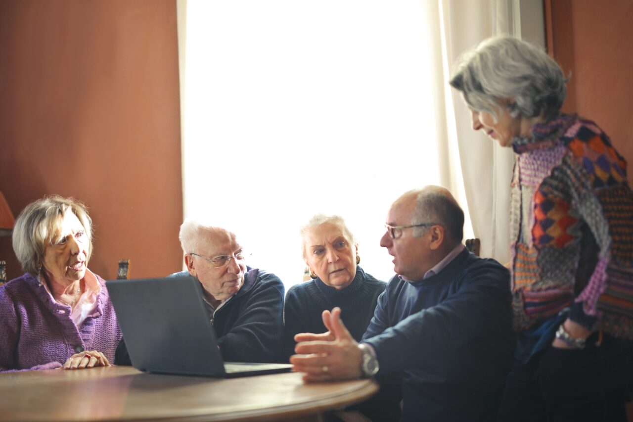 Personas mayores reunidas alrededor de un ordenador portátil