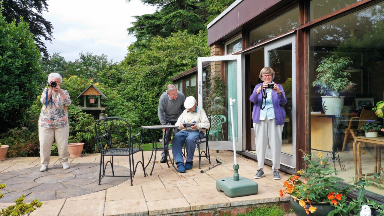 Grupo de personas mayores realizando una actividad de fotografía en un jardín