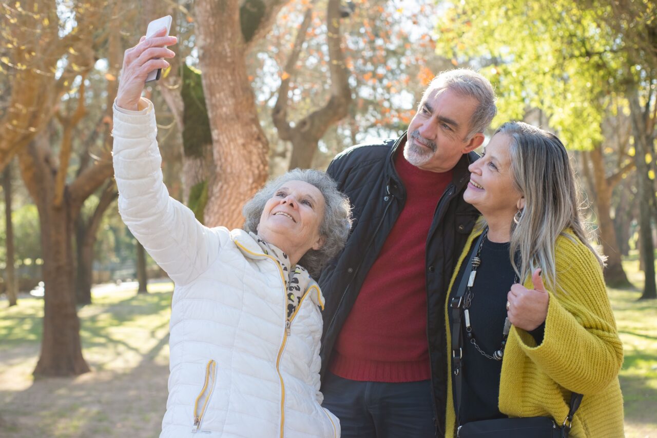 Tres personas mayores haciéndose una fotografía juntas en un parque